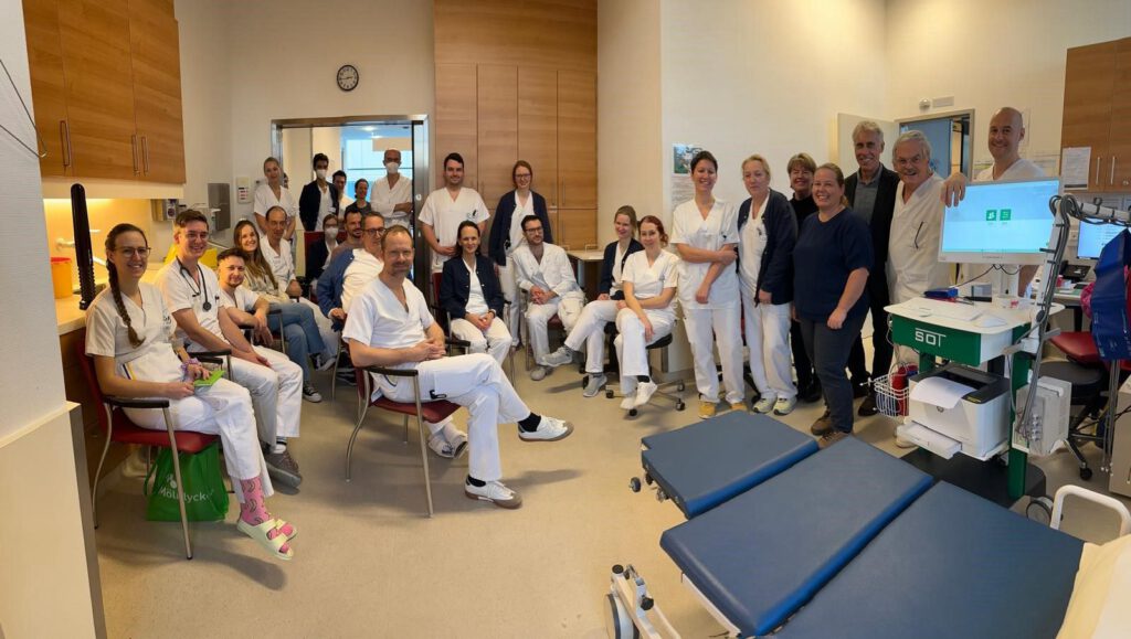 Gruppenfoto mit dem medizinischen Team des Landesklinikums Melk und Vertreter:innen von SOT Medical Systems bei einer Geräteeinschulung. Im Vordergrund sichtbar: das AngE™-System auf einem SOT-Trolley zur Gefäßdiagnostik.